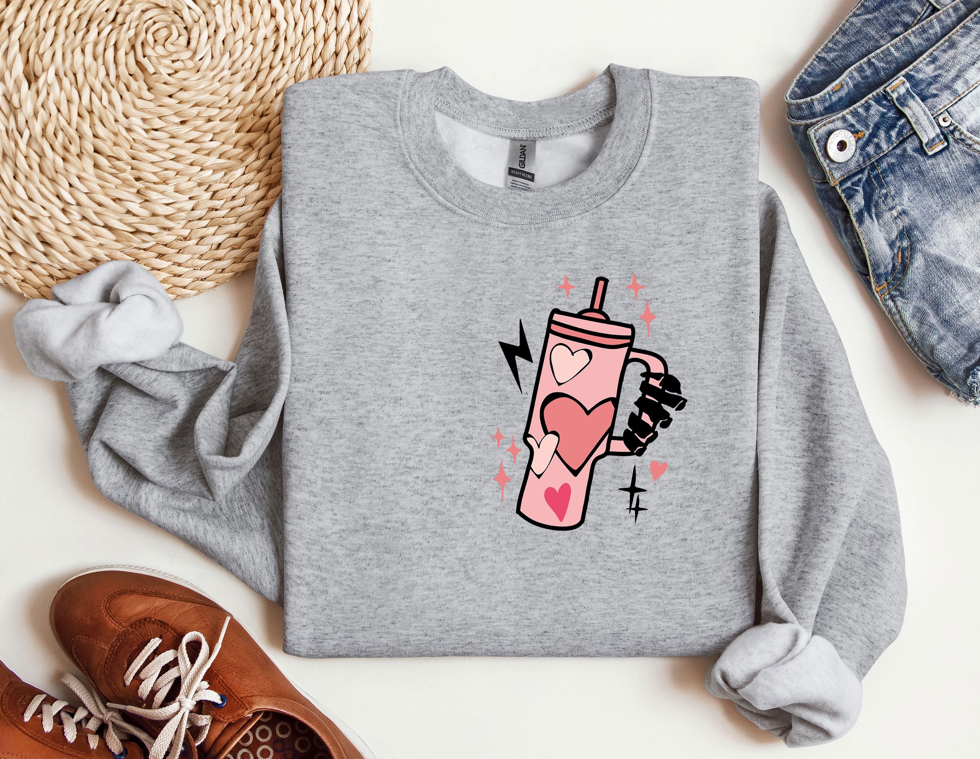 a gray sweatshirt with a pink drink on it