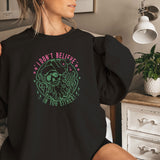 a woman sitting on a bed wearing a black sweatshirt