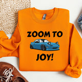 an orange shirt with a blue car that says zoom to joy
