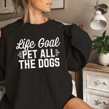 a woman sitting on a bed wearing a black shirt that says life goal pet all