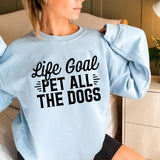 a woman sitting on a bed wearing a blue sweatshirt
