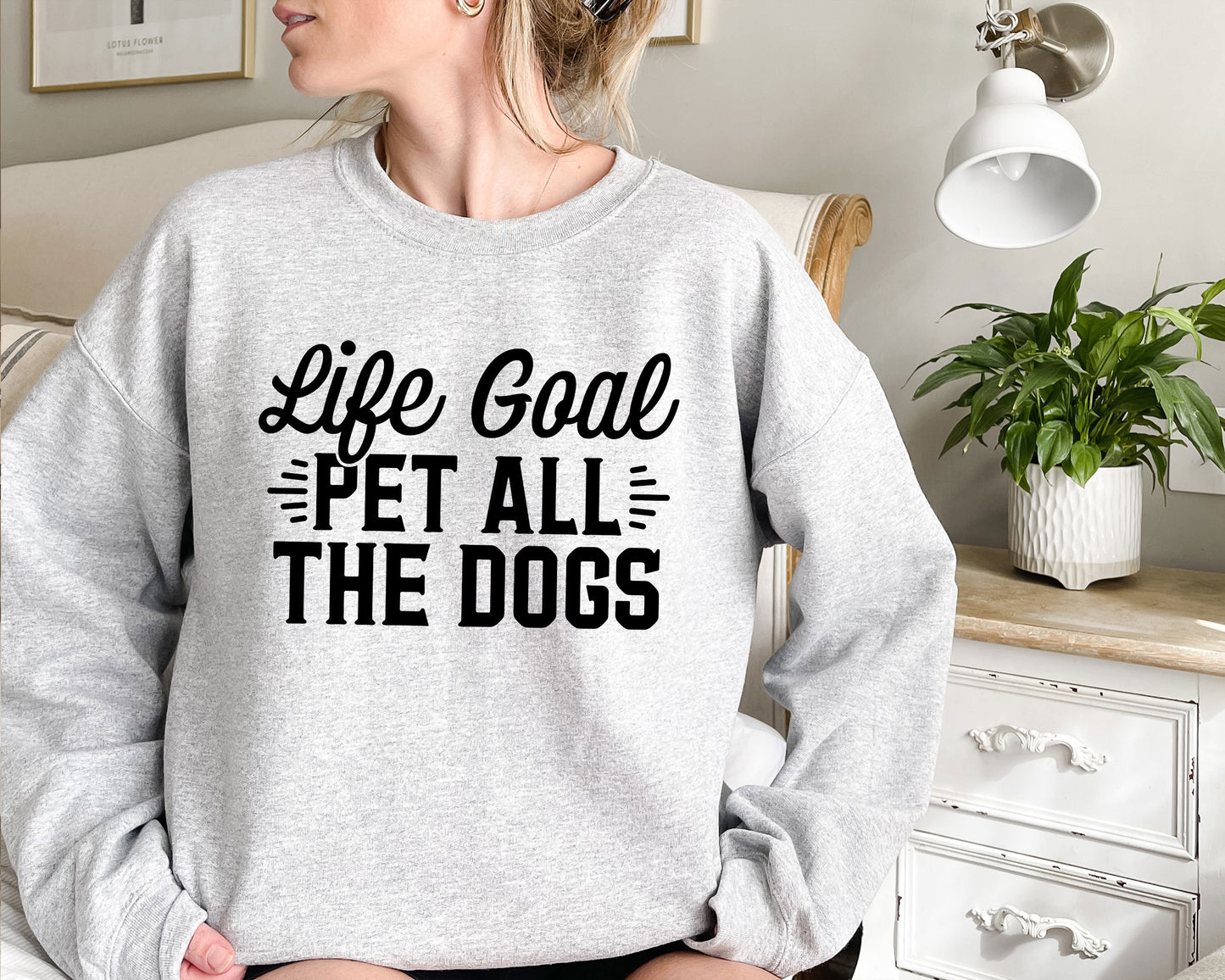 a woman wearing a sweatshirt that says life goal pet all the dogs