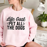 a woman sitting on a bed wearing a pink sweatshirt