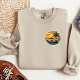 a sweater with a palm tree on it next to a pair of shoes