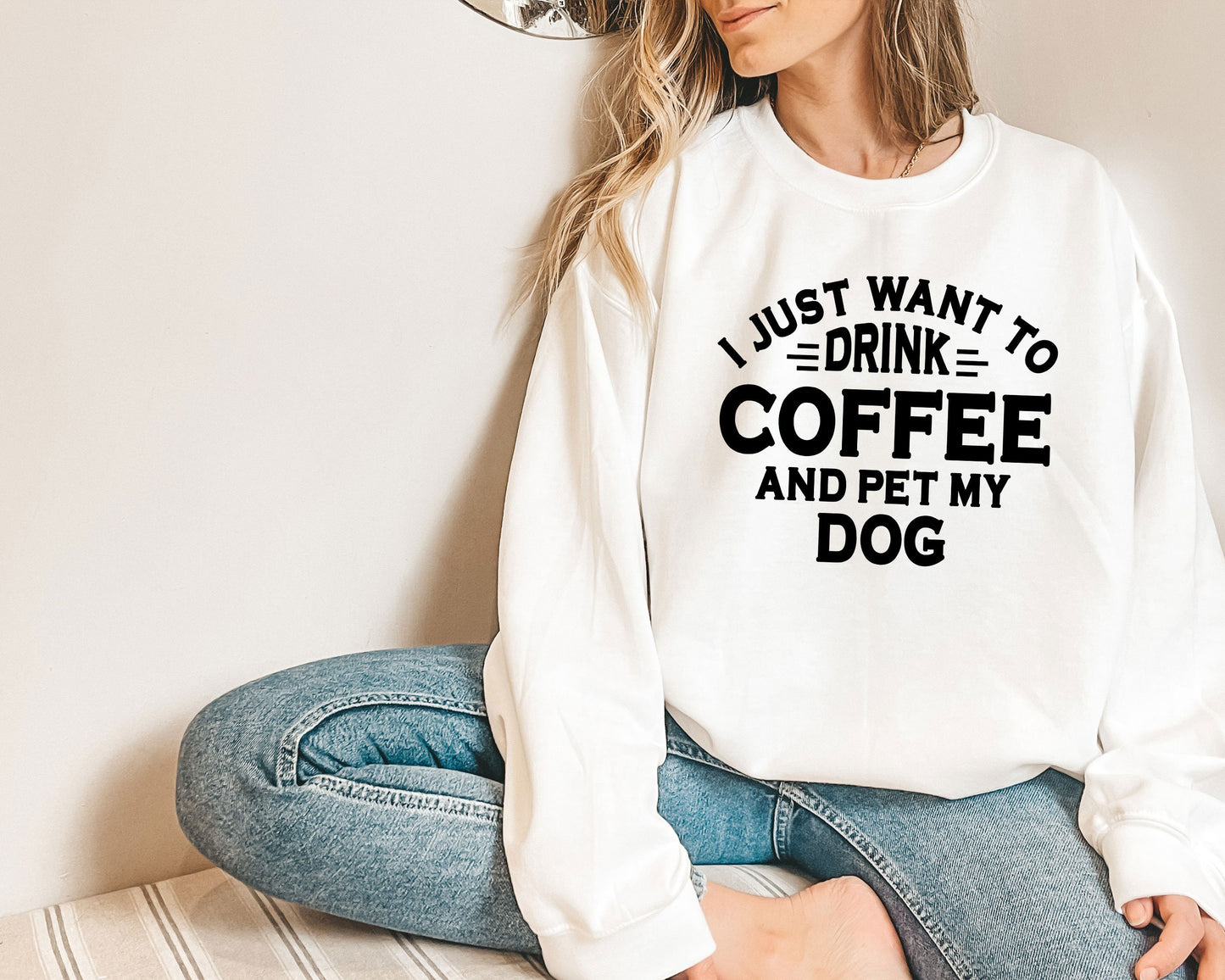 a woman sitting on the floor wearing a sweatshirt that says i just want to drink