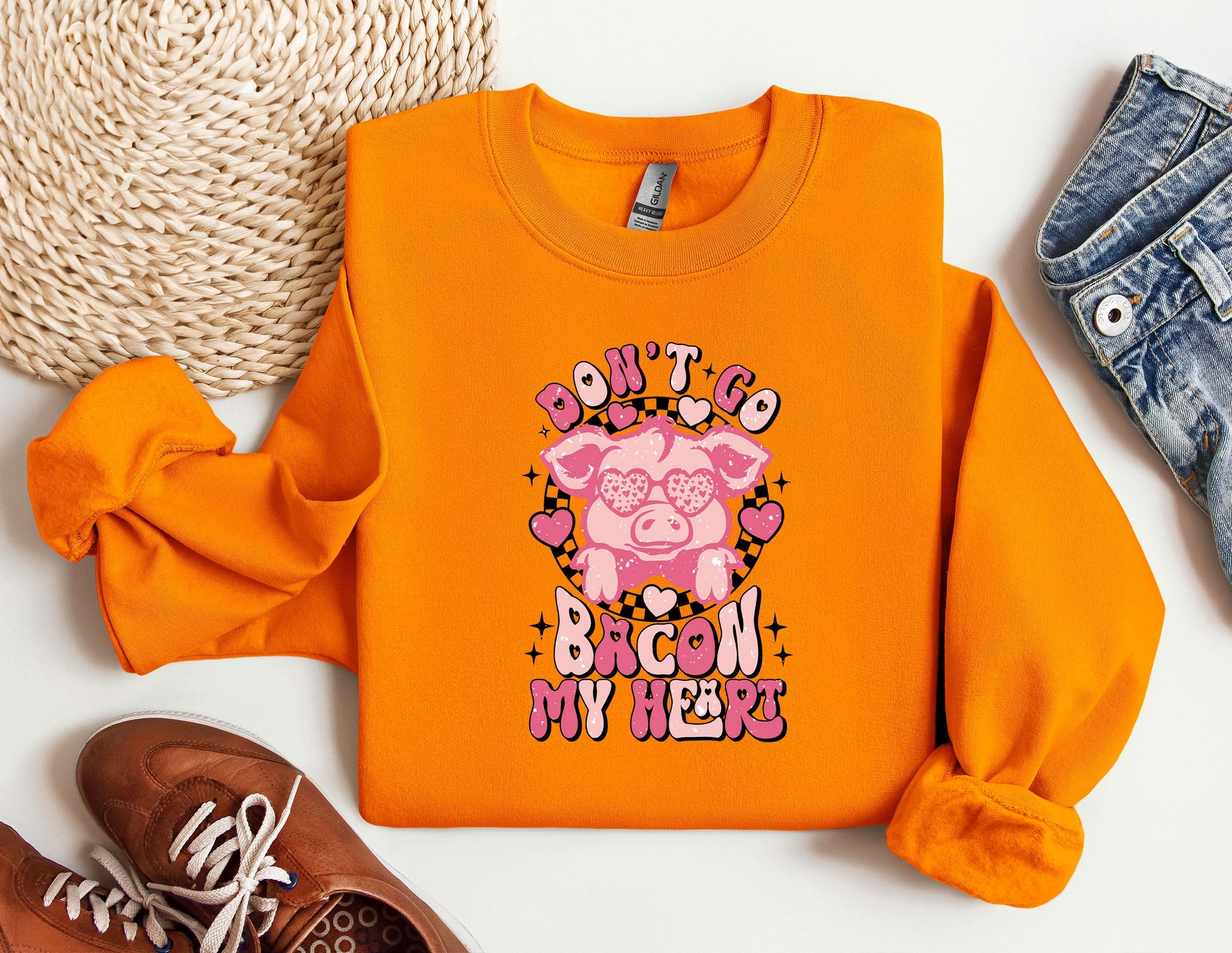 an orange shirt with a pig on it next to a pair of shoes