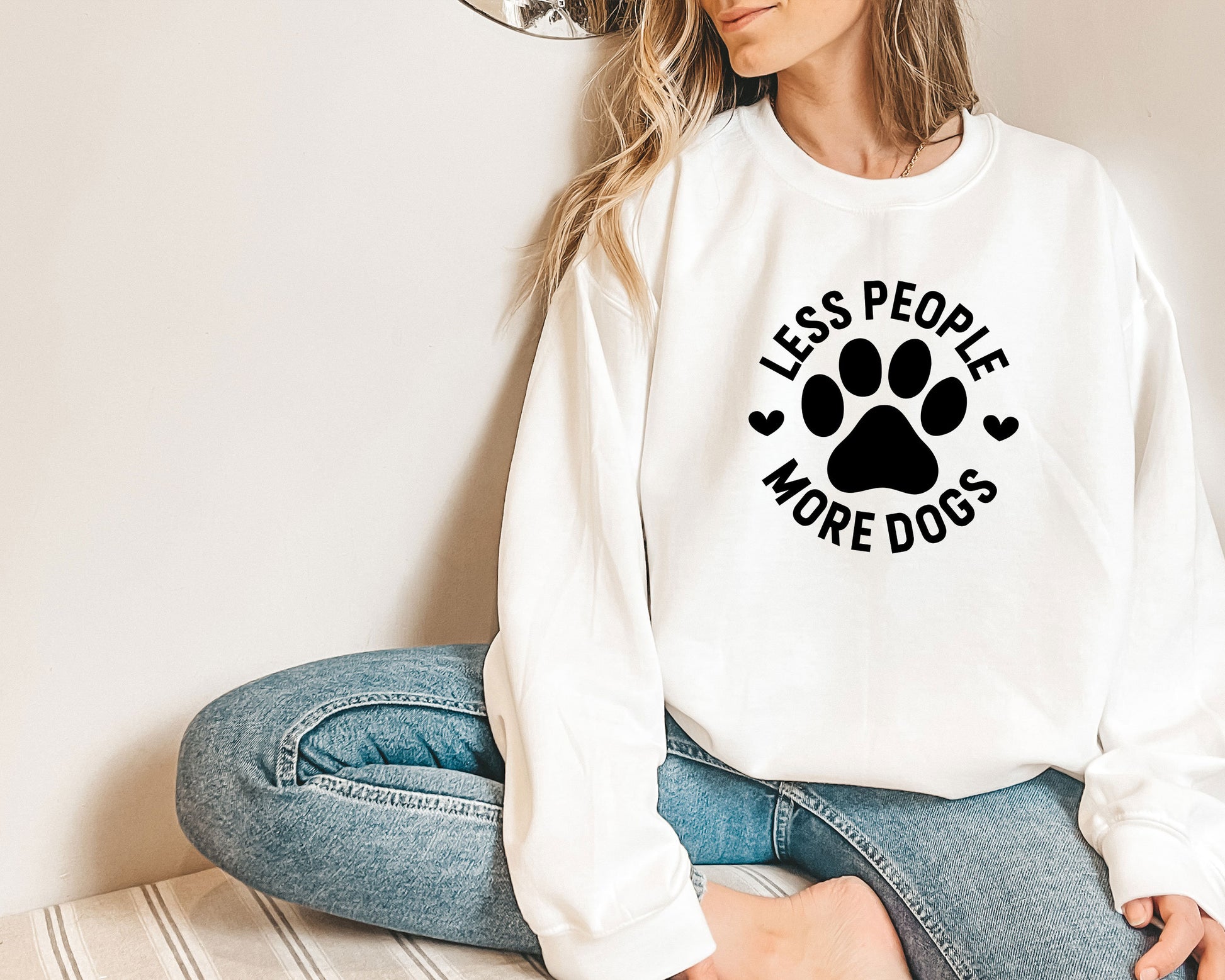 a woman sitting on the floor wearing a sweatshirt with a dog&#39;s paw on