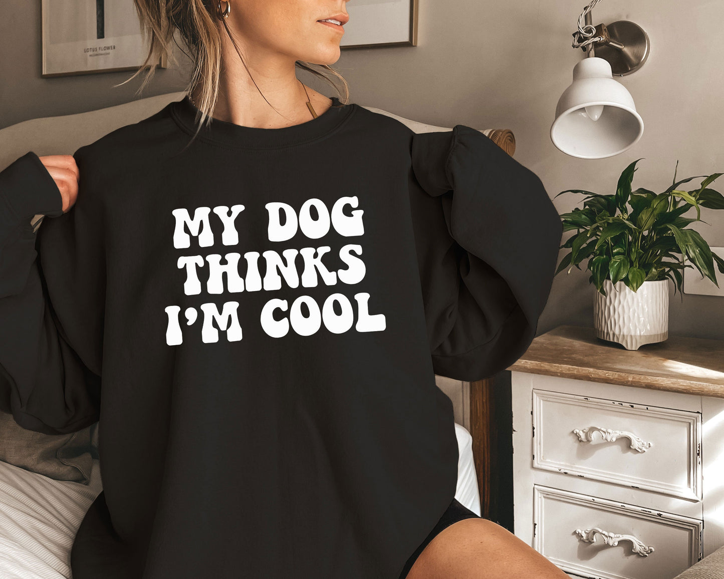 a woman sitting on a bed wearing a black shirt that says, my dog thinks