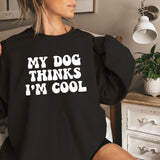 a woman sitting on a bed wearing a black shirt that says, my dog thinks