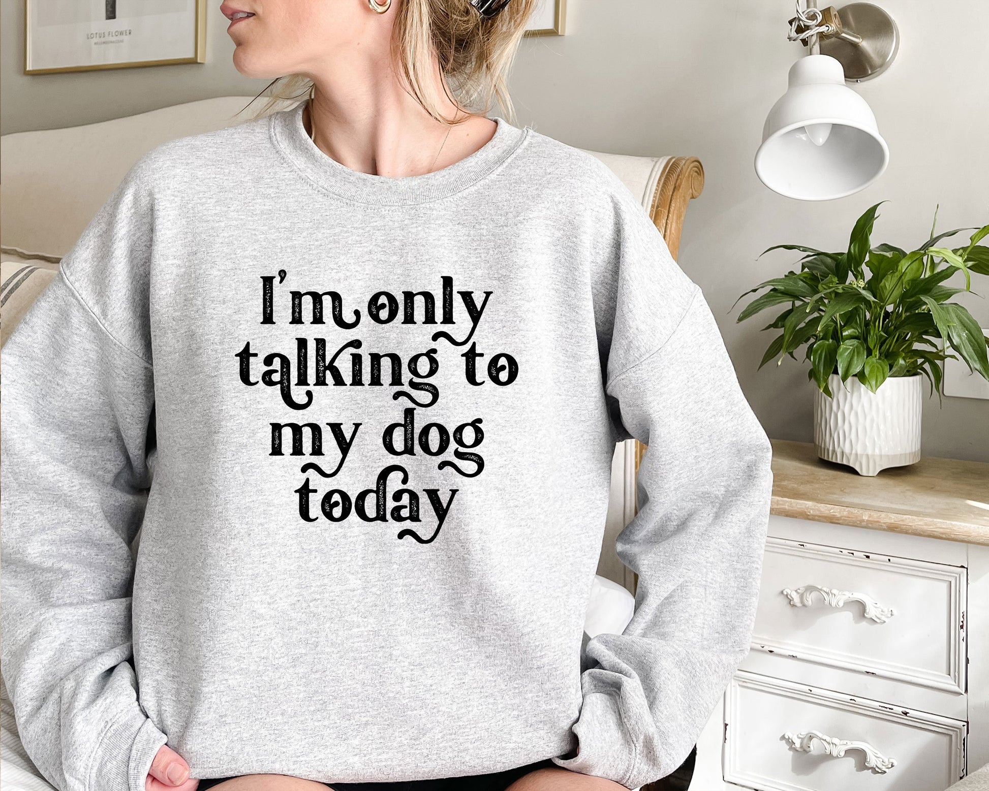 a woman sitting on a bed wearing a sweatshirt that says i&#39;m only talking