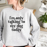 a woman sitting on a bed wearing a sweatshirt that says i'm only talking