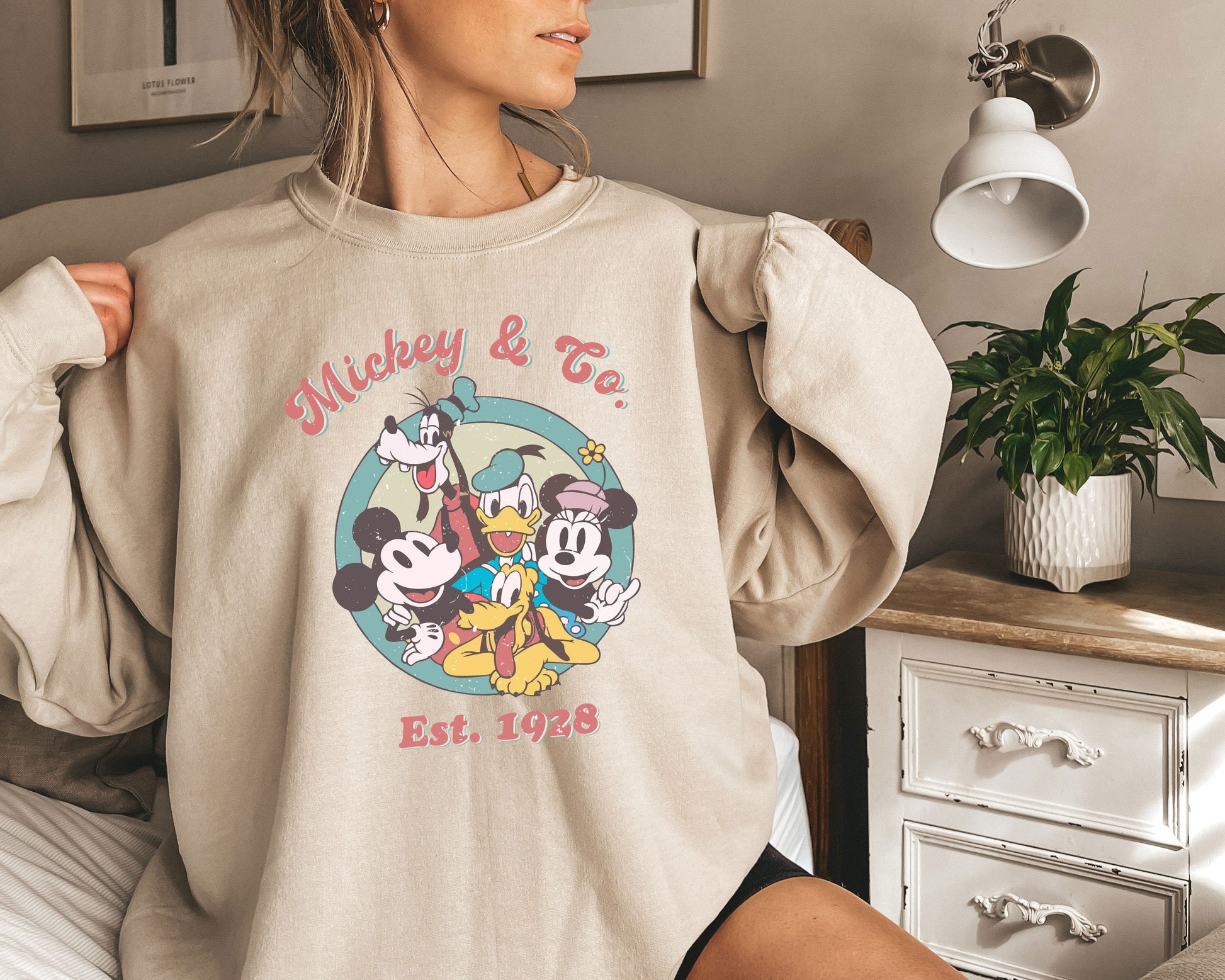 a woman wearing a mickey and friends sweatshirt