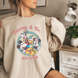a woman wearing a mickey and friends sweatshirt