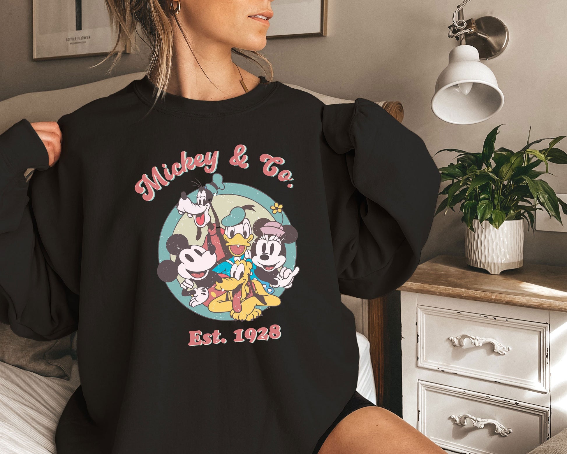 a woman in a mickey and friends shirt on a bed