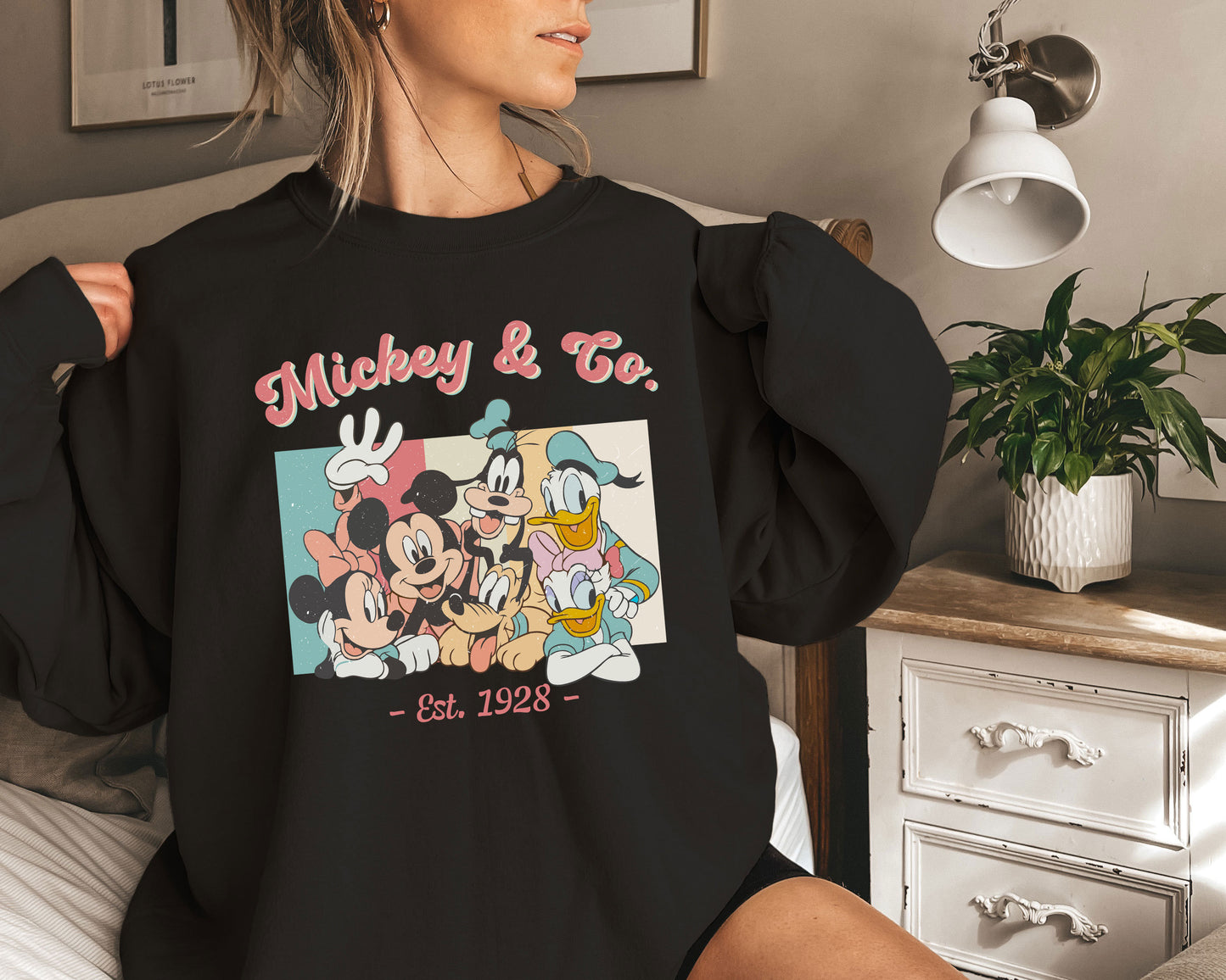 a woman sitting on a bed holding onto a mickey mouse shirt