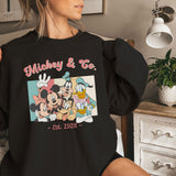 a woman sitting on a bed holding onto a mickey mouse shirt