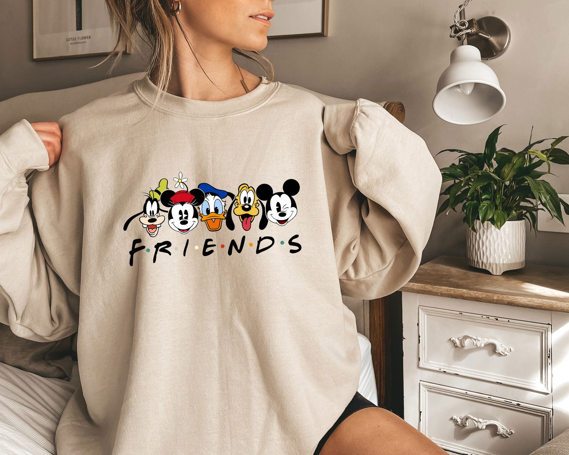 a woman wearing a sweatshirt with mickey mouse friends on it