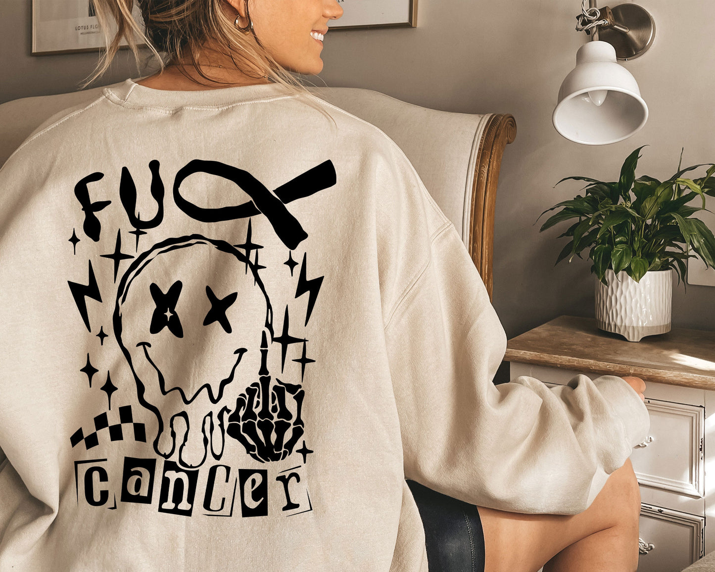 a woman sitting in a chair wearing a sweatshirt with a skull on it