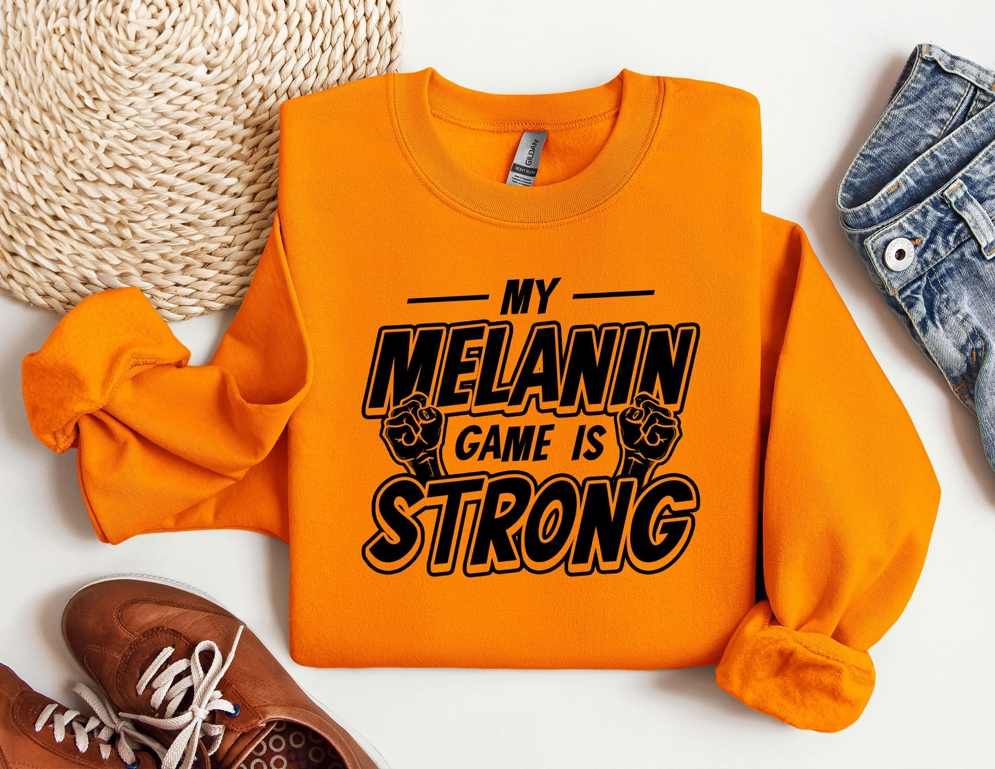 an orange sweatshirt that says my melanin game is strong