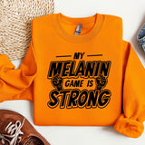 an orange sweatshirt that says my melanin game is strong