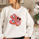 a woman sitting on a bed wearing a mickey mouse sweatshirt
