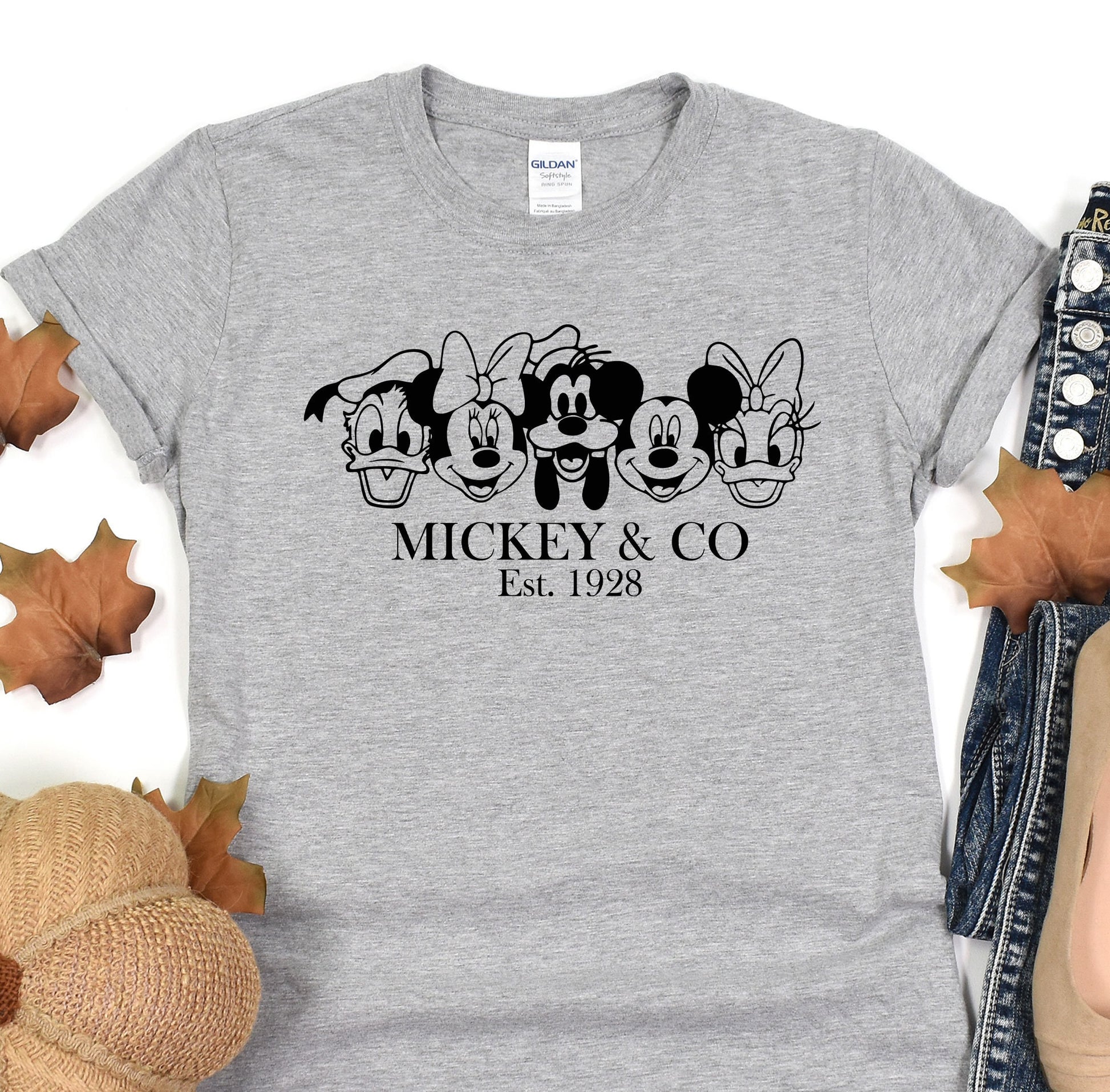 a mickey and mickey mouse t - shirt sitting on top of a pile of leaves