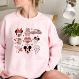 a woman sitting on a bed wearing a pink sweatshirt