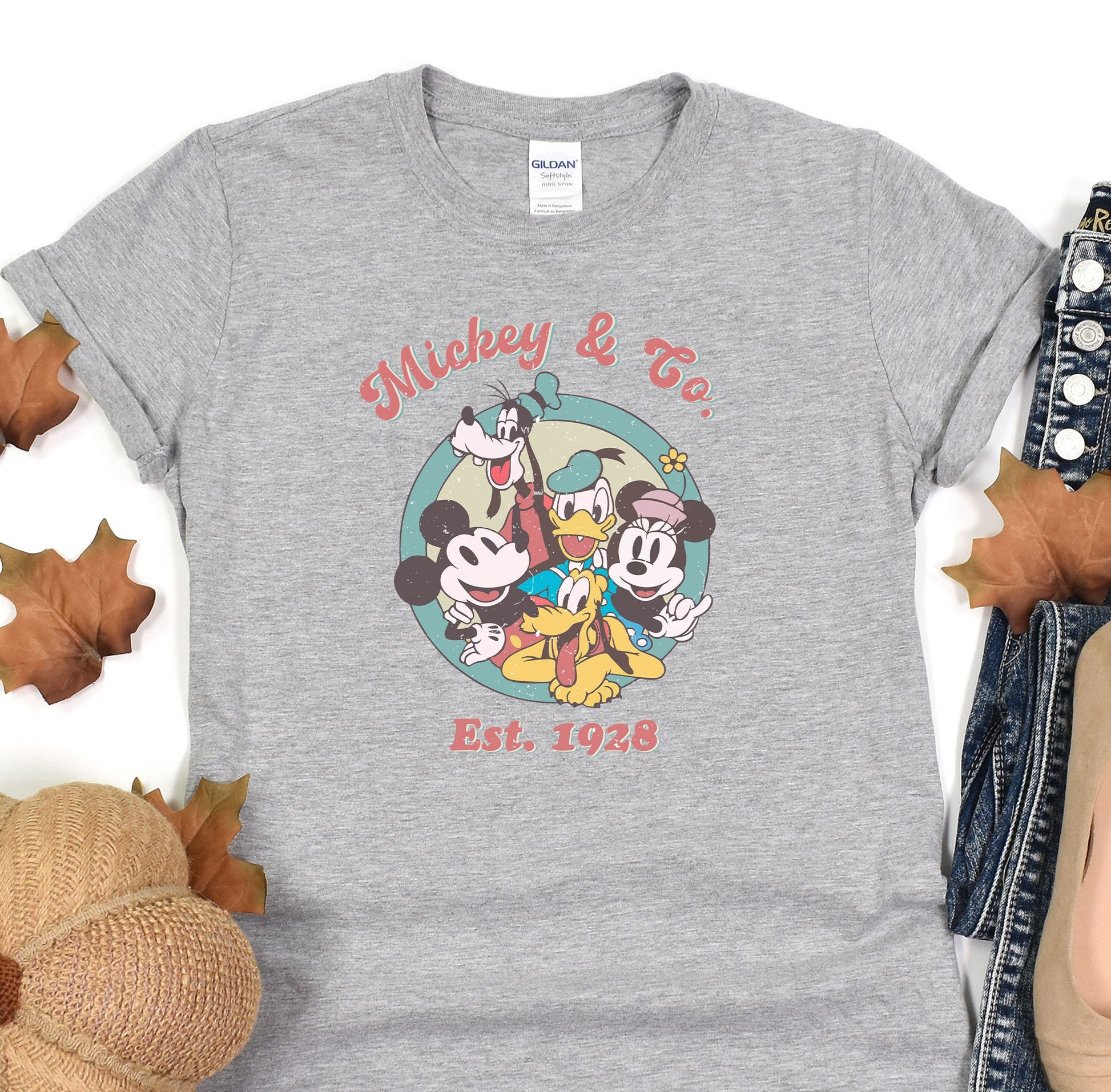 a mickey mouse and friends t - shirt sitting on top of a pile of leaves
