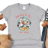 a mickey mouse and friends t - shirt sitting on top of a pile of leaves