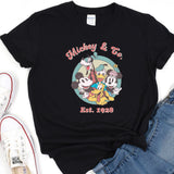a mickey mouse and friends t - shirt sitting on top of a pair of jeans
