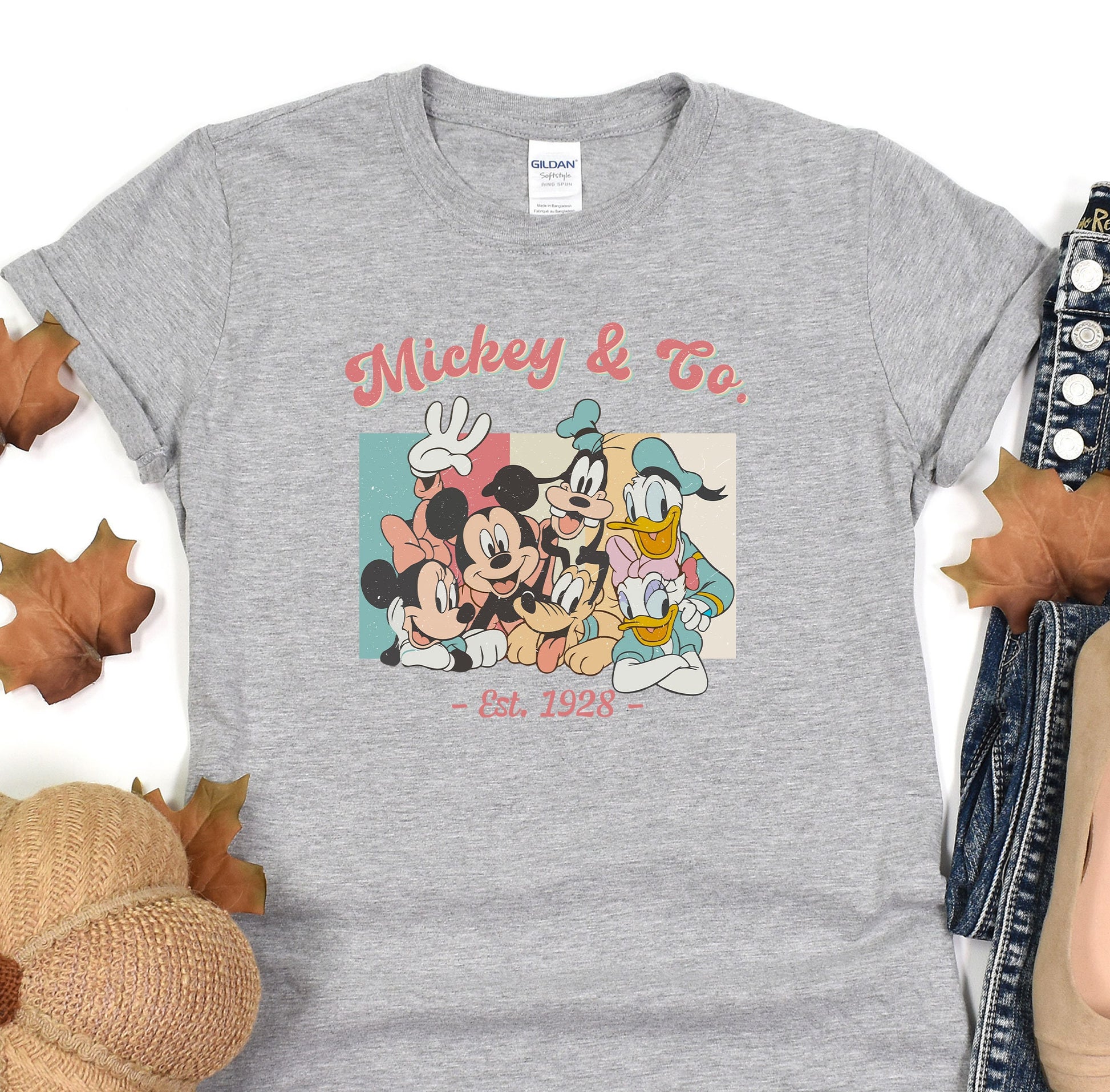 a mickey and mickey mouse t - shirt sitting on top of a pile of leaves