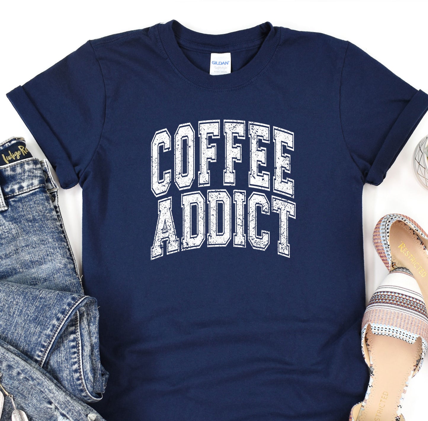 a t - shirt that says coffee addict next to a pair of jeans