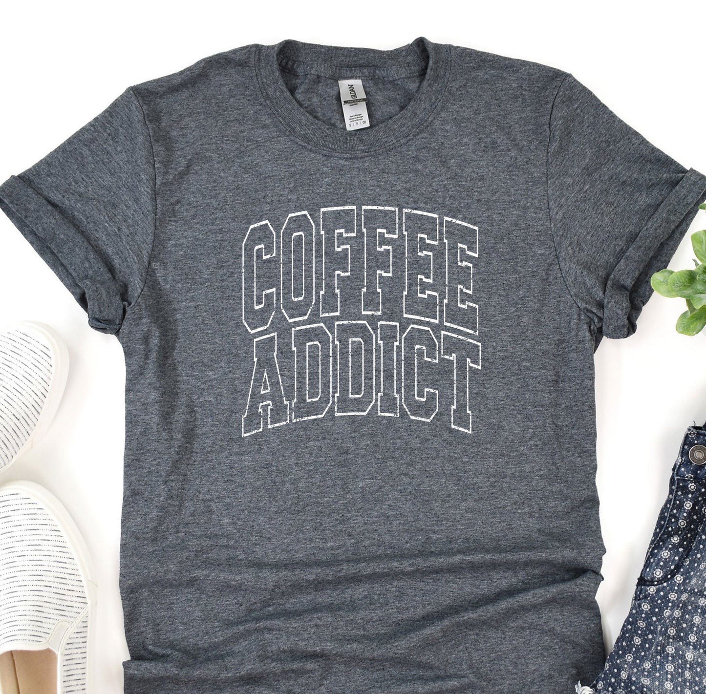 a t - shirt that says coffee addict next to a pair of shoes