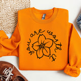 an orange shirt with a flower on it next to a pair of shoes