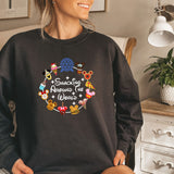 a woman sitting on a bed wearing a black sweatshirt