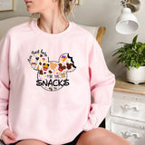 a woman sitting on a bed wearing a pink sweatshirt