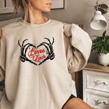 a woman is sitting on a bed wearing a sweatshirt