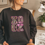 a woman sitting on a bed wearing a black sweatshirt