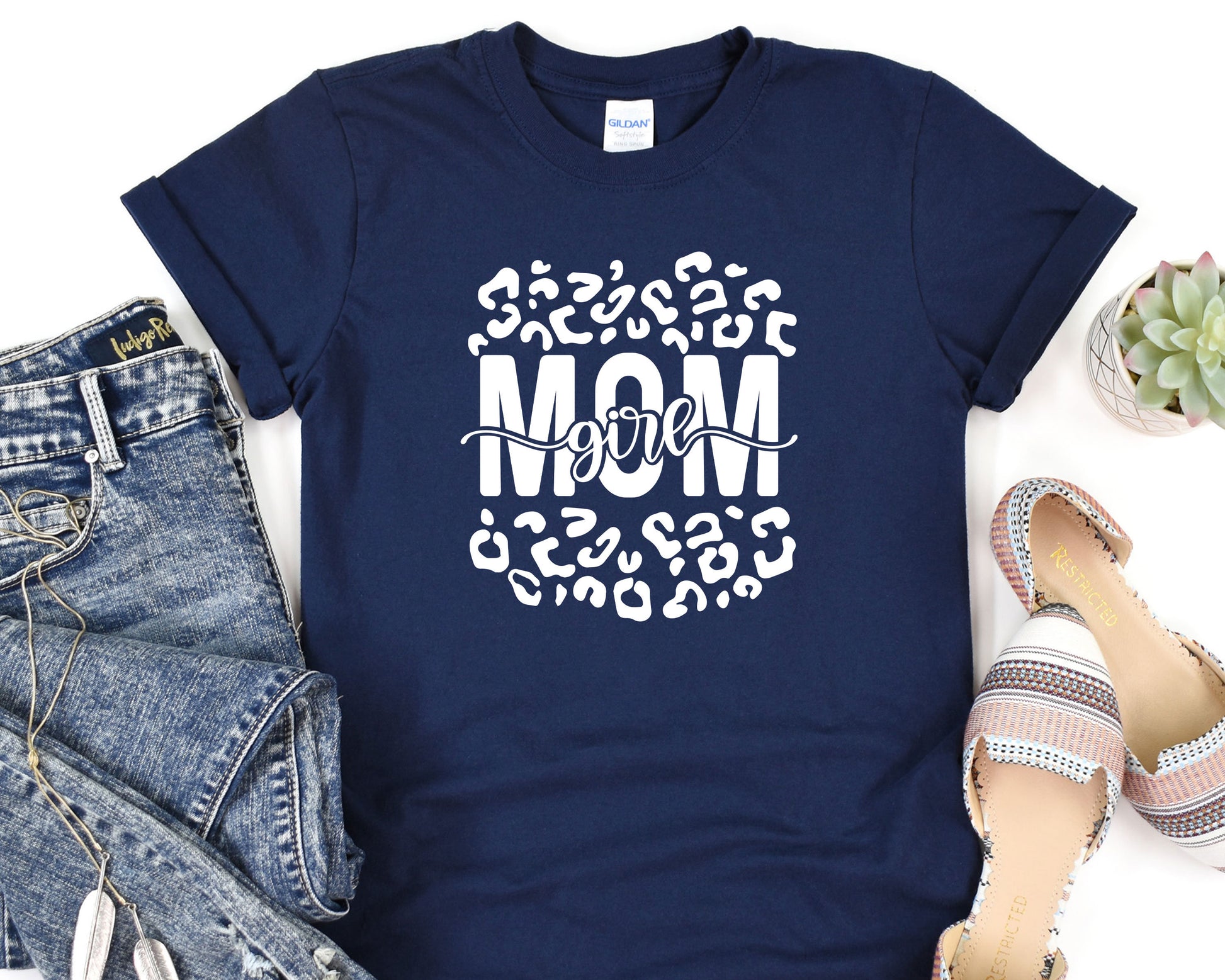 a t - shirt with the words mom on it next to a pair of jeans