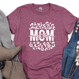 a t - shirt with the words mom on it next to a pair of jeans