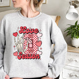 a woman sitting on a bed wearing a sweatshirt