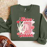 a green sweatshirt with a picture of a house and hearts on it