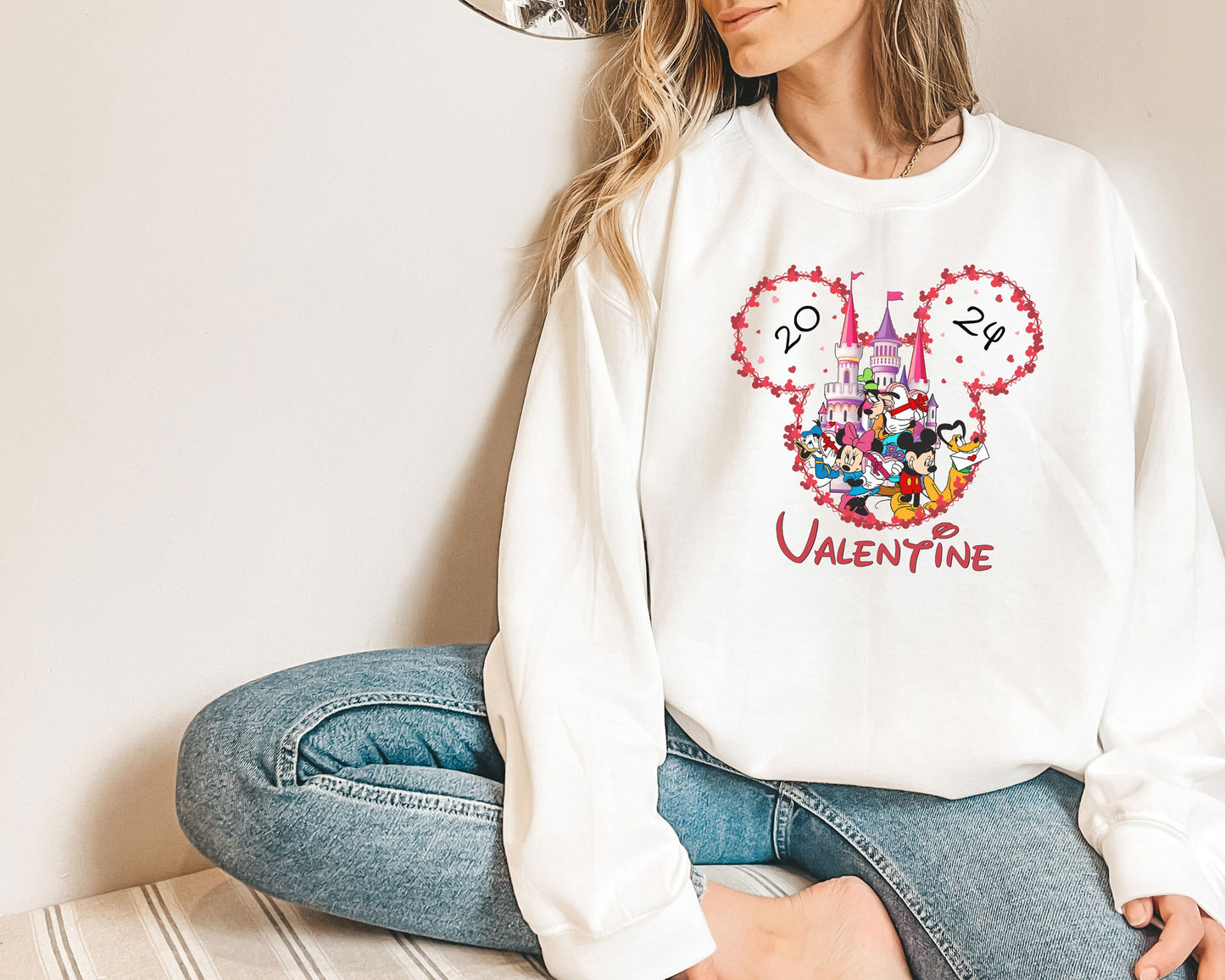 a woman sitting on the floor wearing a mickey mouse sweatshirt