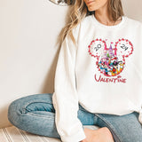 a woman sitting on the floor wearing a mickey mouse sweatshirt