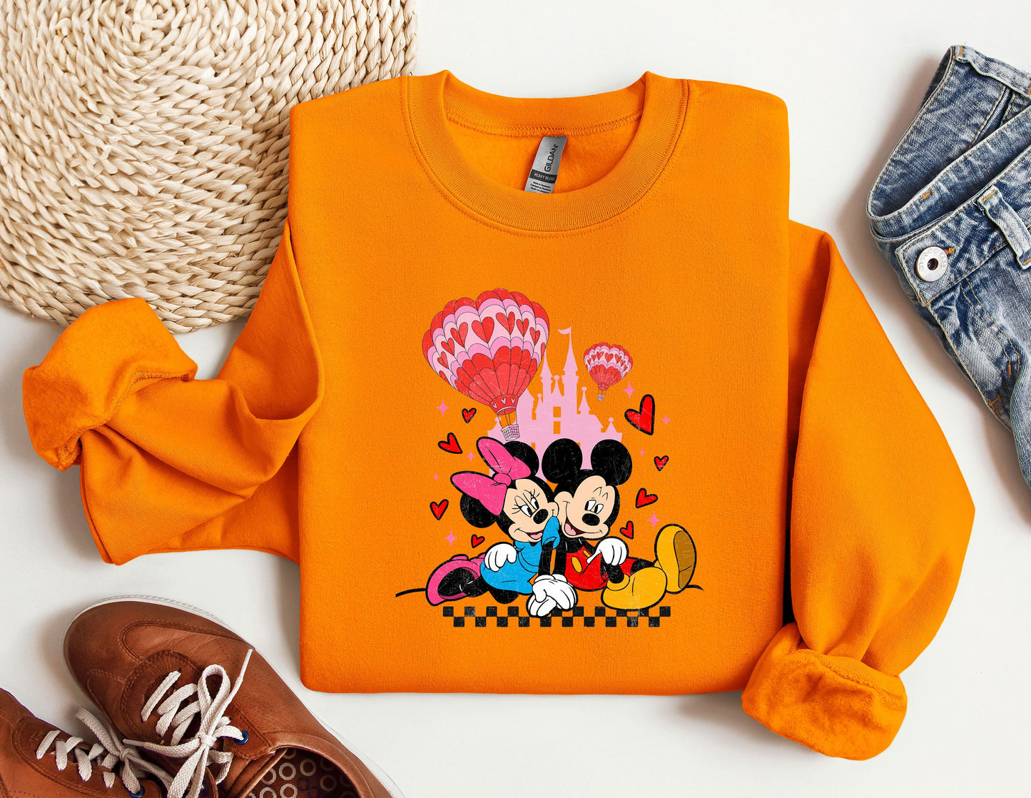 a pair of shoes and an orange sweatshirt with mickey and minnie on it