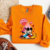 a pair of shoes and an orange sweatshirt with mickey and minnie on it