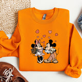 a pair of sneakers and an orange shirt with mickey and minnie on it