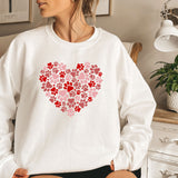 a woman sitting on a bed wearing a sweatshirt with a heart made of paw prints