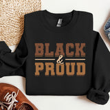a black and proud shirt next to a pair of sneakers