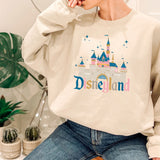a woman sitting on a stool wearing a disneyland sweatshirt